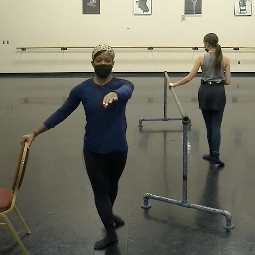 Ursula stands at a chair, Elle stands at the barre
